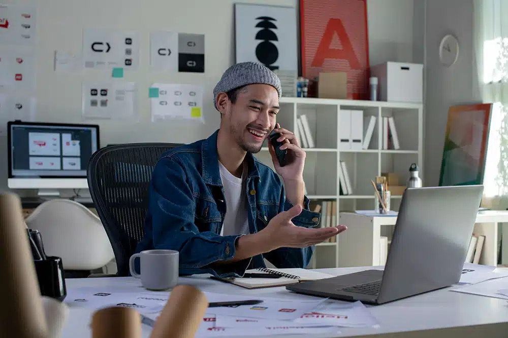 Web developer taking a call on a mobile, whilst using his laptop